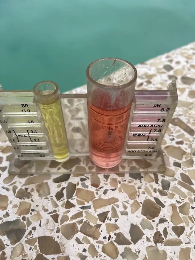 Pool water test kit showing chlorine and pH levels on a pool deck